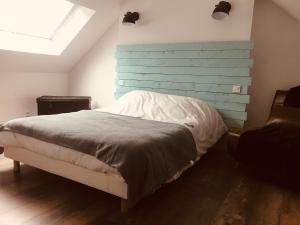 ein Schlafzimmer mit einem Bett mit einer blauen Wand in der Unterkunft Maison en pierre entièrement rénovée. in Trébry