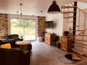 ein Wohnzimmer mit einer Treppe und einem Tisch in der Unterkunft Maison en pierre entièrement rénovée. in Trébry