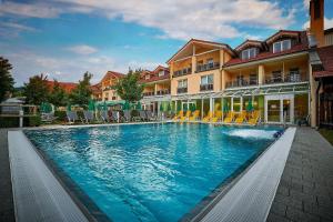 a swimming pool with chairs in front of a building at Hotel Herzog Heinrich in Arrach