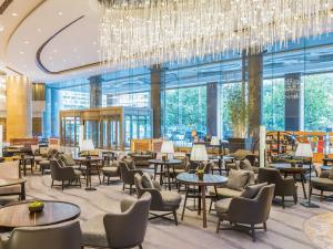 a lobby with tables and chairs and a chandelier at New World Dalian Hotel in Dalian