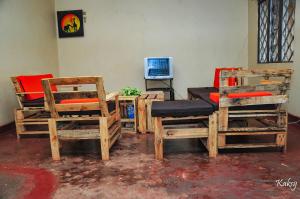 a room with chairs and a table and a television at Venchester Guest House in Jinja