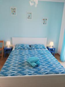 un letto con piumone blu e due tavoli di Apartments Relax Punat a Punat