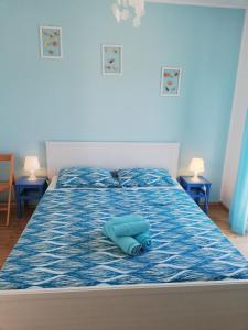 łóżko z niebieską kołdrą z dwoma stołami w obiekcie Apartments Relax Punat w mieście Punat