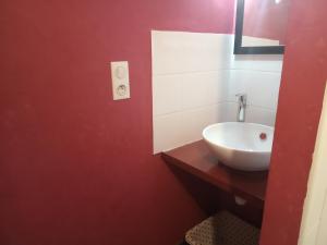 La salle de bains est pourvue d'un lavabo blanc et d'un mur rouge. dans l'établissement Les attelages de la fontaine, à Épothémont