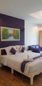 a bedroom with a large white bed with purple walls at Jasmine Chiangmai Boutique Hotel in Chiang Mai