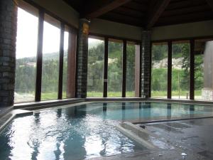 a swimming pool in a building with windows at 151 Manoir Savoie - ARC 1950 in Arc 1950