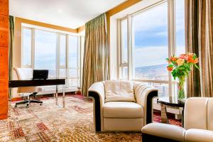 a living room with a piano and a room with windows at Best Western Premier Tuushin Hotel in Ulaanbaatar