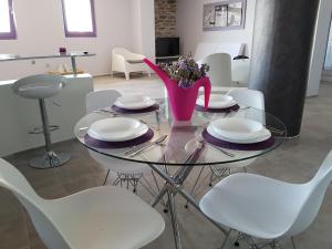 a glass table with white chairs and a vase with flowers at Apartment at KiVA-villa, Kampi, KEA, Cyclades, Greece in Ligia