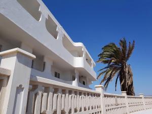 ein weißes Gebäude mit einem Zaun und einer Palme in der Unterkunft Superbe appartement à Costa Antigua in Costa de Antigua