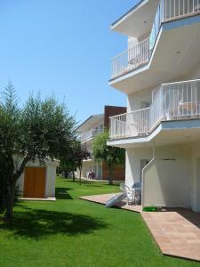 a white building with a grass yard and a tree at Apartamentos Sunway Atlanta in Sitges