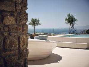 a large white tub sitting next to a stone wall at Arcs Boutique Villa Hotel in Mikonos