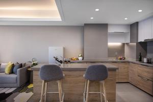 a kitchen with two bar stools and a couch at Citadines Keqiao Shaoxing in Shaoxing