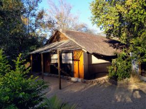 a small house with a thatched roof in the woods at Off Beat Safaris Bush Lodge in Hoedspruit