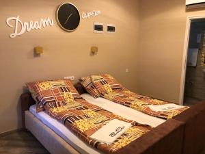 two beds in a room with a clock on the wall at Barna Bár Motel&Apartman in Tetélen