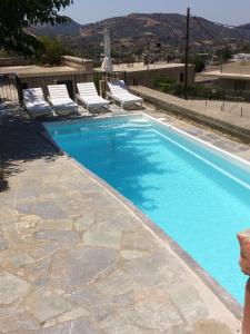 a swimming pool with chairs and a swimming pool at Nana Apartments in Zarós