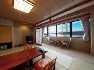 ein Wohnzimmer mit einem Tisch und Stühlen sowie einem großen Fenster in der Unterkunft Naruto Kaigetsu in Naruto