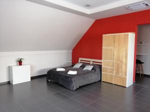 a bedroom with a bed and a red wall at Szépségpatika Apartman in Sárospatak