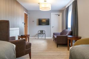 a living room with a couch and chairs and a tv at Samlesbury Hotel in Preston