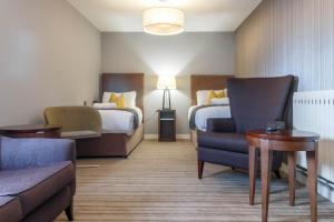 プレストンにあるSamlesbury Hotelのベッド2台、椅子、ソファが備わるホテルルームです。