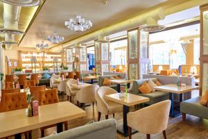 a restaurant with tables and chairs and windows at Vostok Hotel in Tyumen