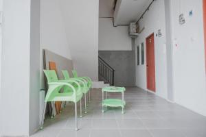 a row of green chairs in a hallway at RedDoorz near Gatot Subroto Lampung 2 in Bandar Lampung