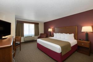a hotel room with a large bed and a television at AmericInn by Wyndham Merrill in Merrill