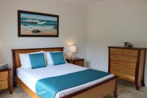 a bedroom with a bed with blue pillows and a dresser at George River Park in St Helens