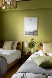 two beds in a room with green walls at Little Santa in Ginowan