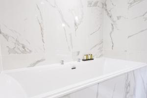 a white bathroom with a white tub and marble walls at The Scotsman Hotel in Edinburgh