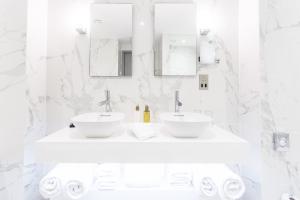 a white bathroom with two sinks and mirrors at The Scotsman Hotel in Edinburgh