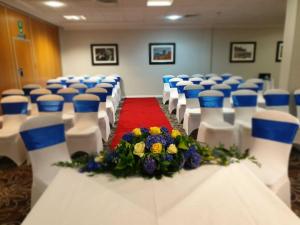 una fila de sillas blancas con alfombra roja y flores en The Worcester Whitehouse Hotel, en Worcester