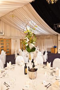 una habitación con una mesa con sillas blancas y un jarrón de flores en Calderfields Golf & Country Club, en Walsall