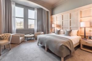 a bedroom with a large bed and a chair at The Scotsman Hotel in Edinburgh
