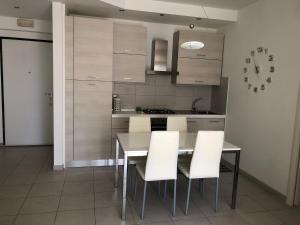 a kitchen with a dining table and white chairs at Le Miromí in Civitanova Marche