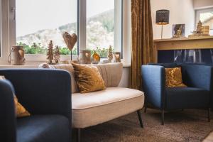 sala de estar con 2 sillas, sofá y ventana en Familienhotel Botenwirt en Kleinarl