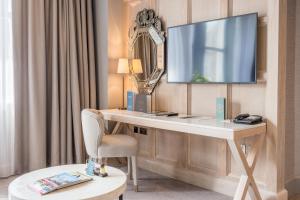 a hotel room with a desk and a television on a wall at The Scotsman Hotel in Edinburgh