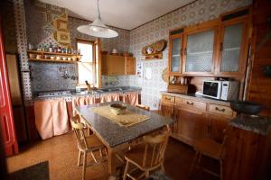 una cucina con tavolo, sedie e forno a microonde di appartamento " Il Ginepro" a Carloforte