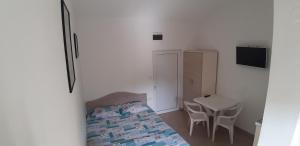 a small bedroom with a bed and a table at Apartmani "Ravić" in Sutomore