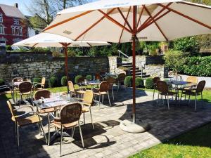 a patio with tables and chairs under an umbrella at Le temps d'une escapade in Silenrieux