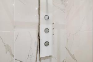 d'une douche avec des murs en marbre blanc et une porte en verre. dans l'établissement Pick A Flat's Apartment in Bastille - Rue du Chemin Vert, à Paris