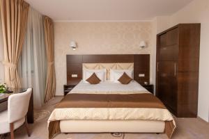 a hotel room with a large bed and a desk at Grand Hotel Coroana in Bistriţa
