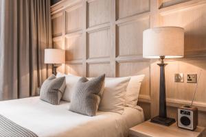 a bedroom with a bed with pillows and a lamp at The Scotsman Hotel in Edinburgh