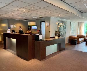 a lobby with a reception desk and a couch at Fletcher Hotel Restaurant Boschoord in Oisterwijk