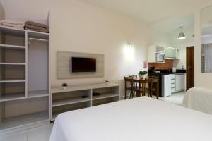 a white bedroom with a bed and a kitchen at Pousada Villa Peixes do Mar in Ubatuba