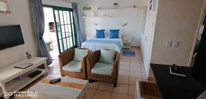 ein Schlafzimmer mit einem Bett mit blauen Kissen und 2 Stühlen in der Unterkunft Private Kaliva 605, Club Mykonos Resort in Langebaan