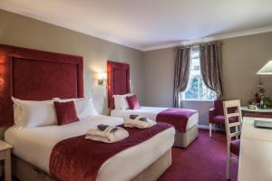 a hotel room with two beds and a desk at Roganstown Hotel & Country Club in Swords