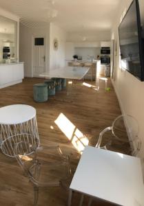 - une cuisine avec des tables et des chaises blanches dans la chambre dans l'établissement APPARTEMENT GRAND CONFORT PORQUEROLLES, à Porquerolles