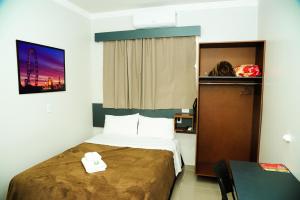 a hotel room with a bed and a table at London Executive Hotel in Cafelândia