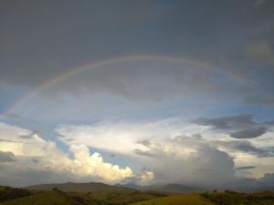 a rainbow in the sky over a mountain at Alvorada Guest House in Caxambu