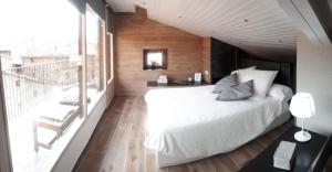 1 dormitorio con cama blanca y balcón en Cal Dalmau Apartaments Átic en Pardines